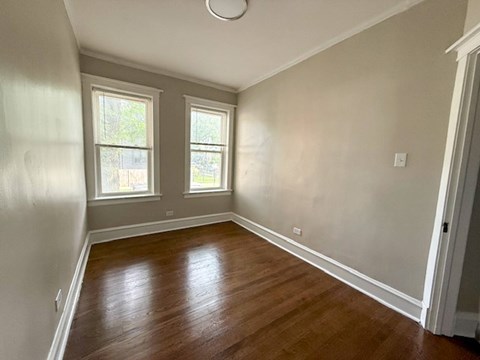 A room with wooden floors and two windows.