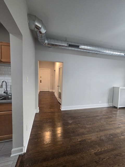 A long hallway with a white wall and a white floor heater.