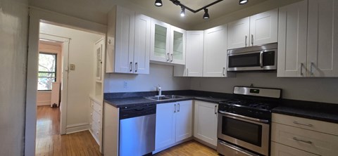 A kitchen with white cabinets and black countertops.