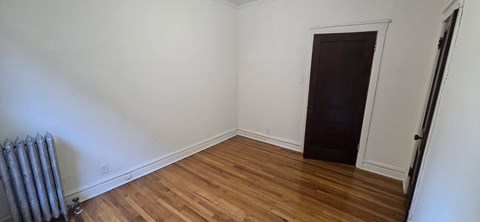 A room with a wooden floor and a door on the right side.