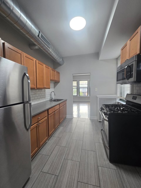 A kitchen with a stainless steel refrigerator and black stove top oven.