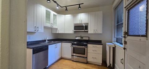 A kitchen with white cabinets and black countertops.