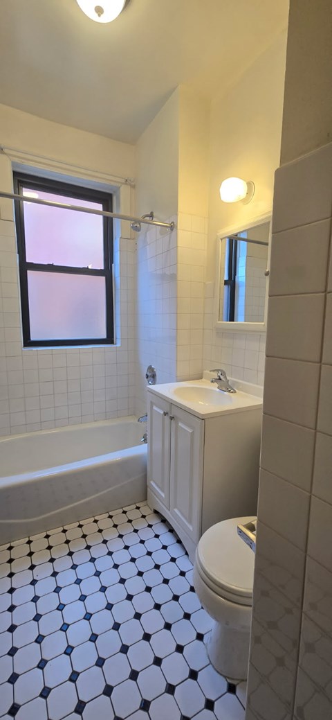 A white bathroom with a black and white tiled floor.