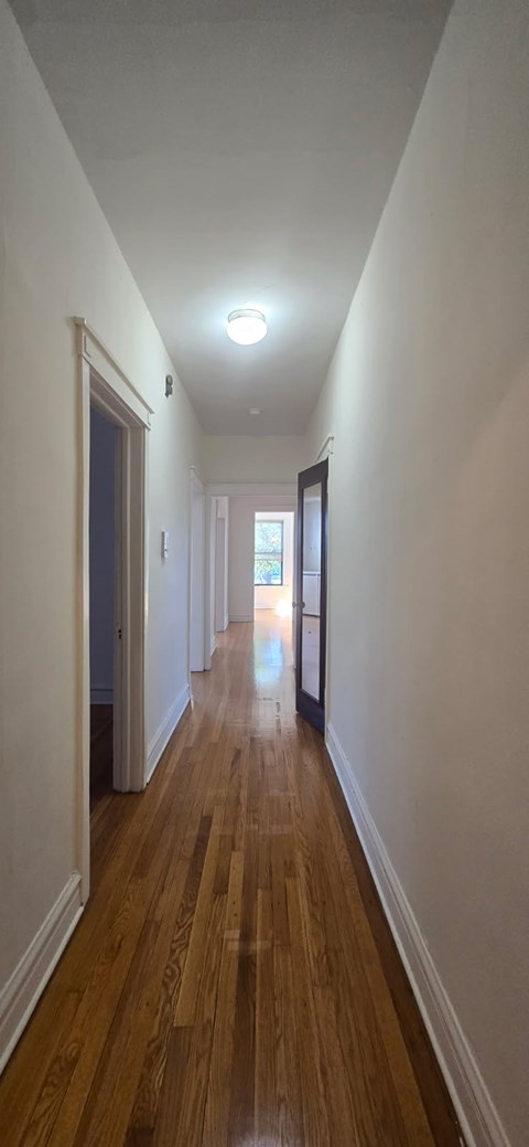 A long hallway with wooden floors and white walls.
