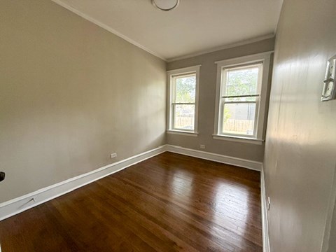 A room with wooden floors and two windows.