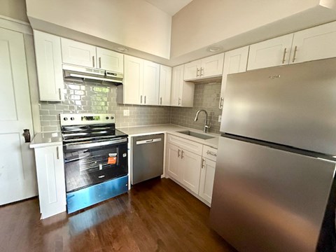 A kitchen with a stove, sink, and refrigerator.