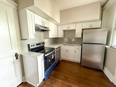 A kitchen with white cabinets and a stainless steel refrigerator.