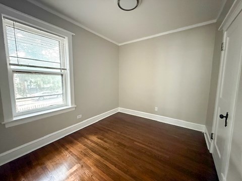 A room with a window and a wooden floor.