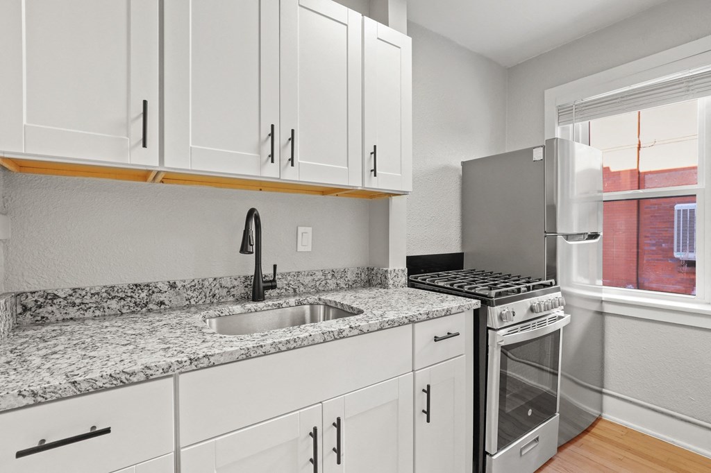 the kitchen has white cabinets and granite counter tops and stainless steel appliances