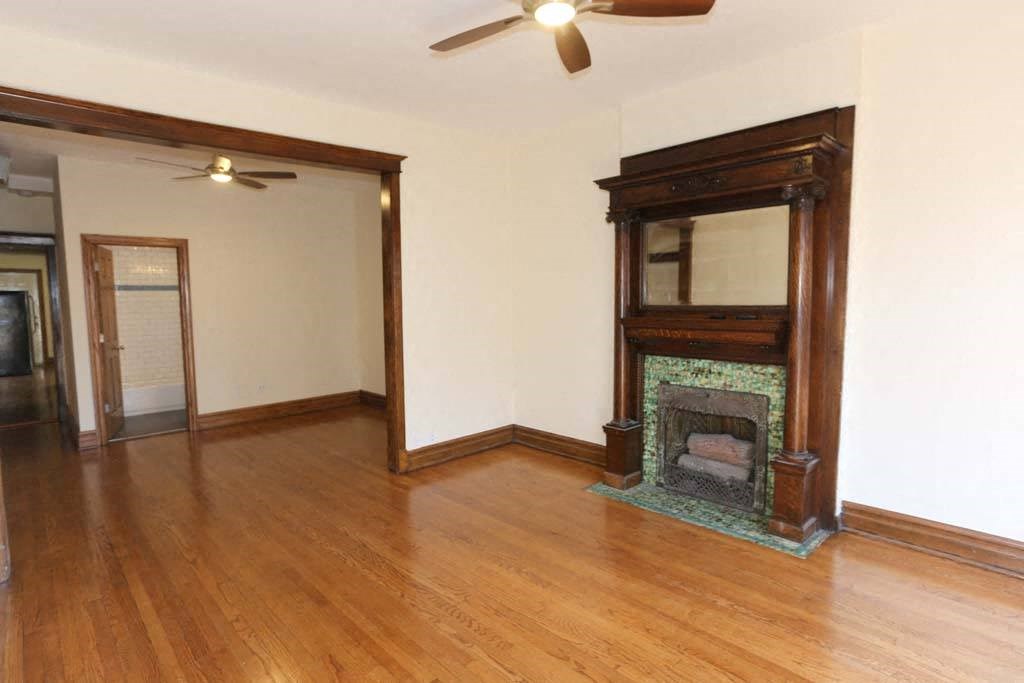 an empty living room with a fireplace and wooden floors