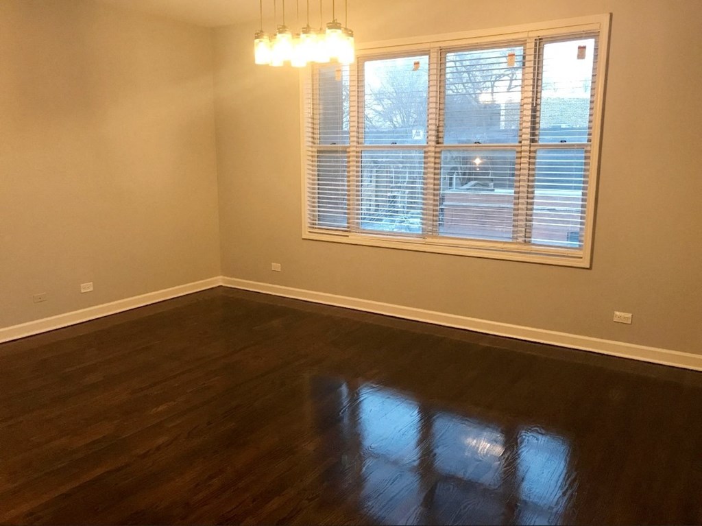 an empty living room with wood floors and a window