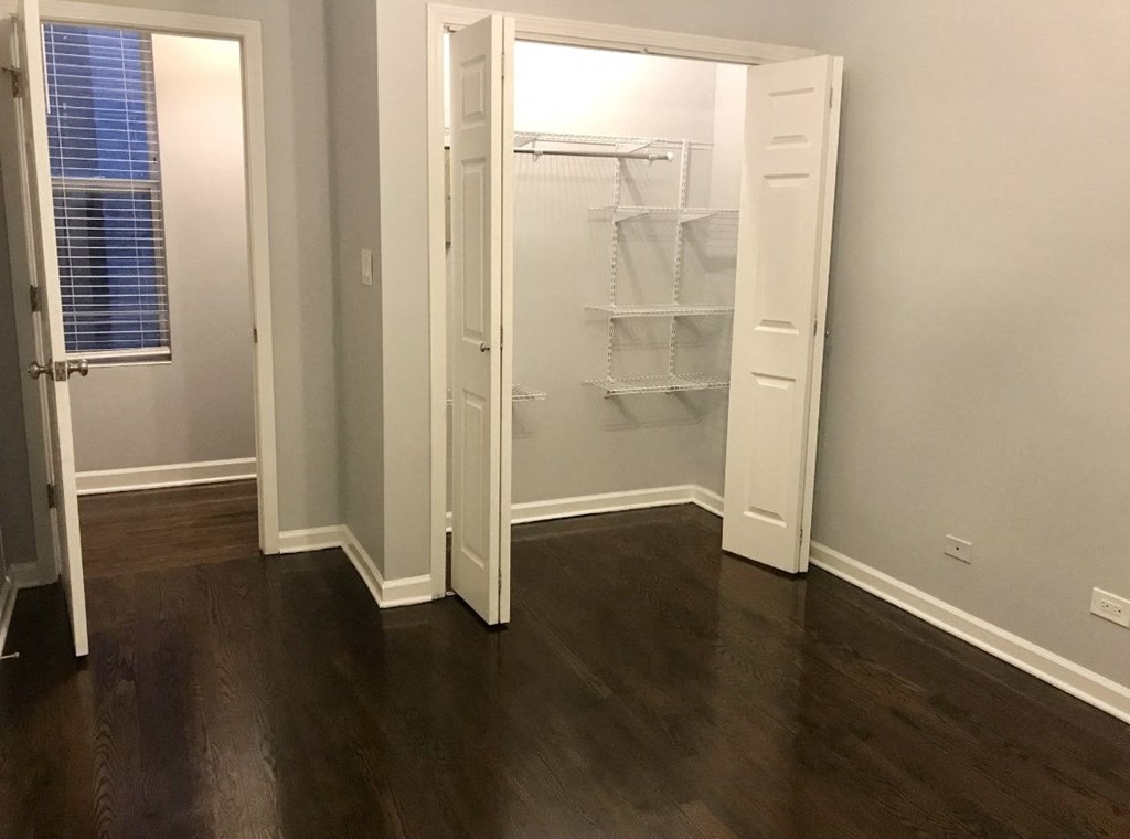 a room with wooden floors and a closet with an open door