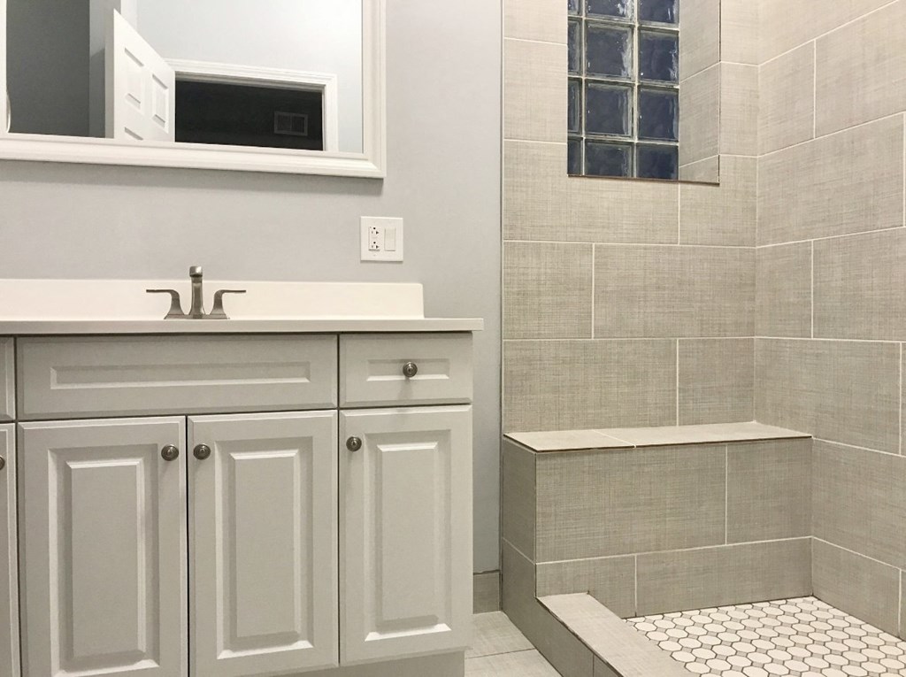 a bathroom with white cabinets and a shower and sink