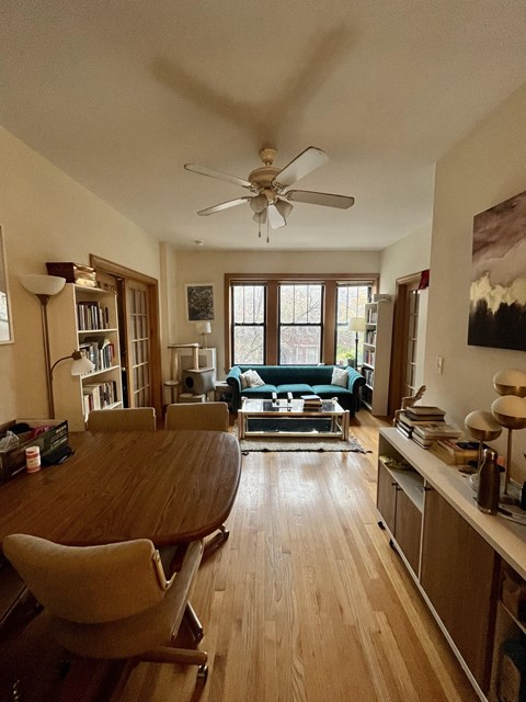 a living room with a table and a ceiling fan