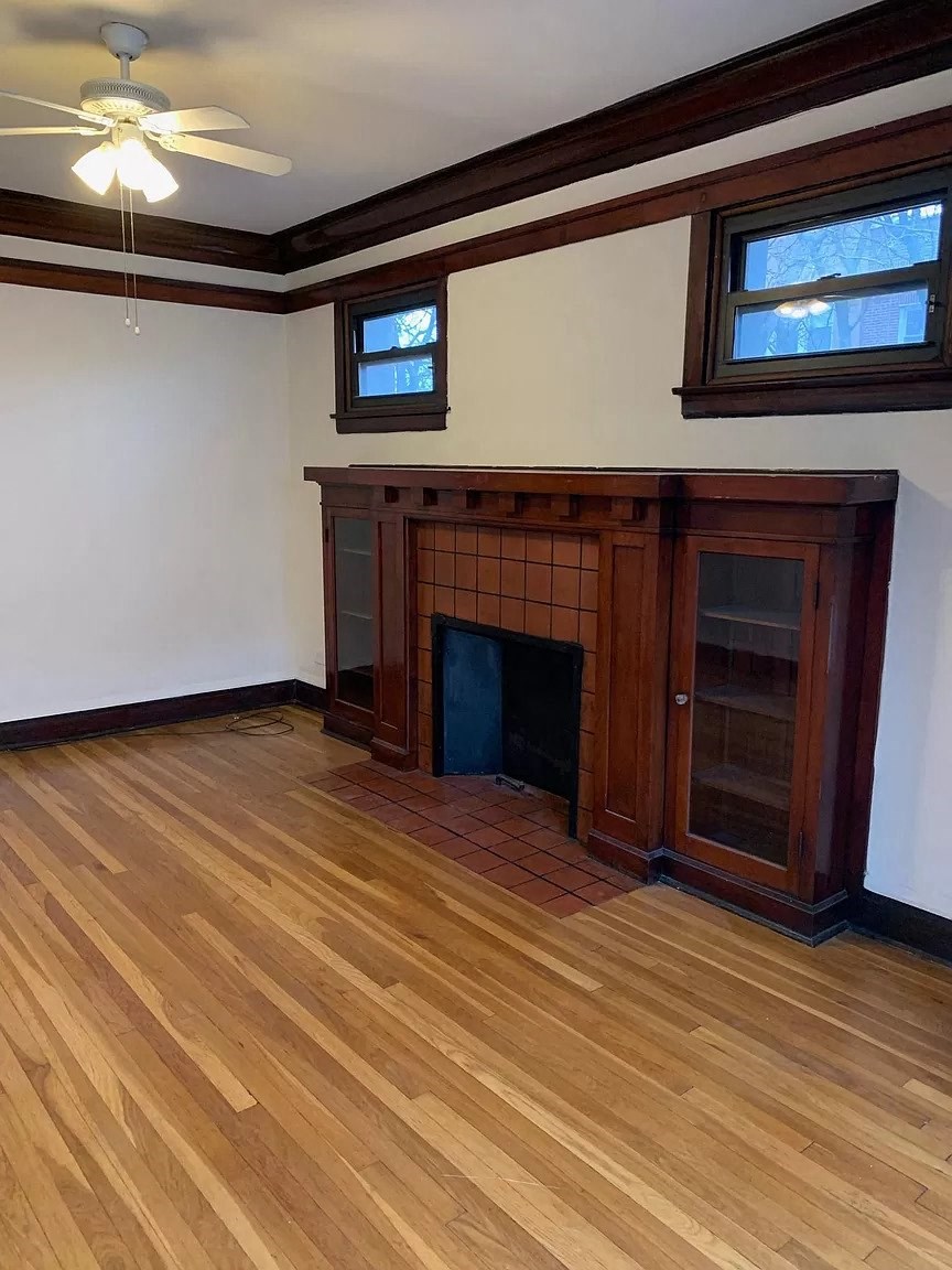 an empty living room with a fireplace and wooden floors