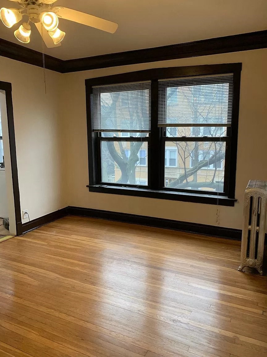 an empty living room with a hard wood floor and large windows