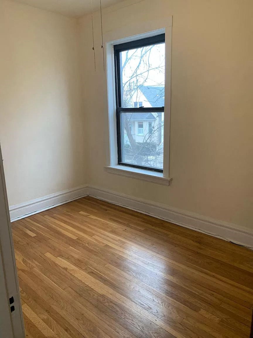 an empty room with a window and wooden floors