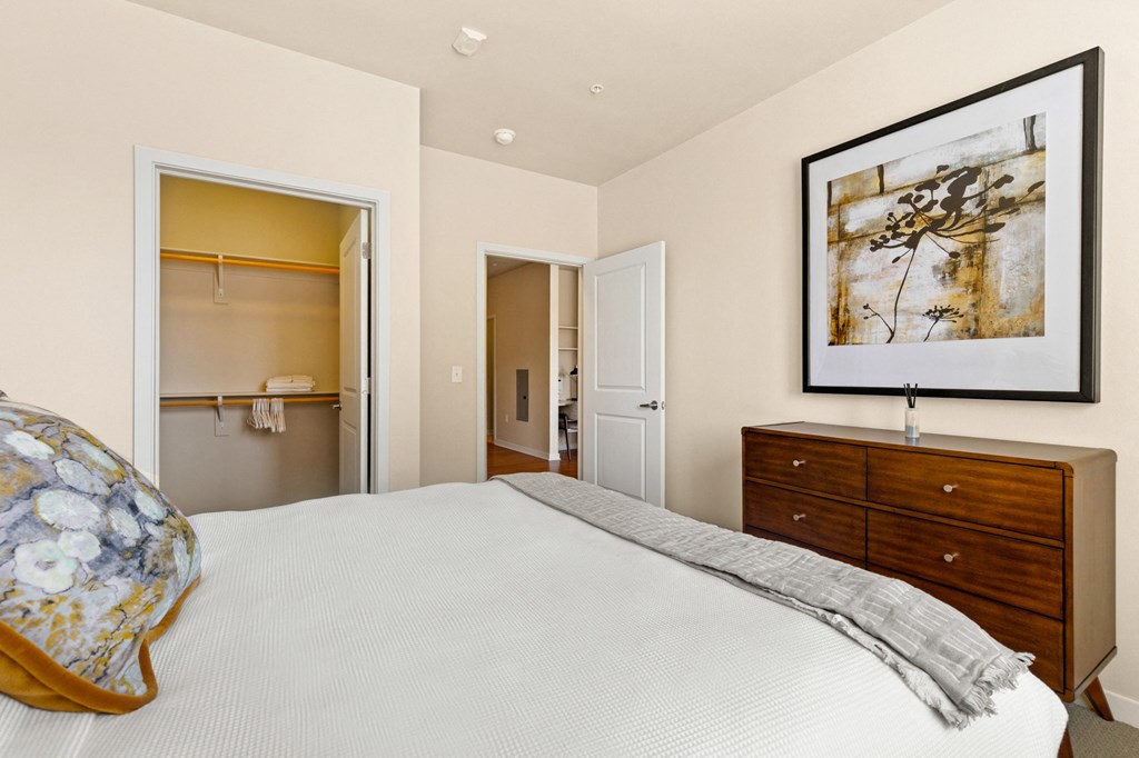 a bedroom with a bed and a dresser and a bathroom