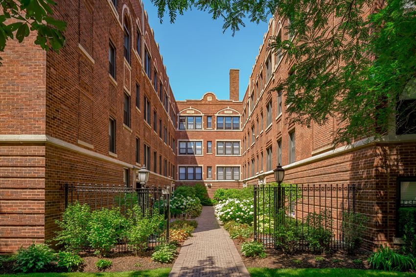 a walkway between two brick buildings in a courtyard