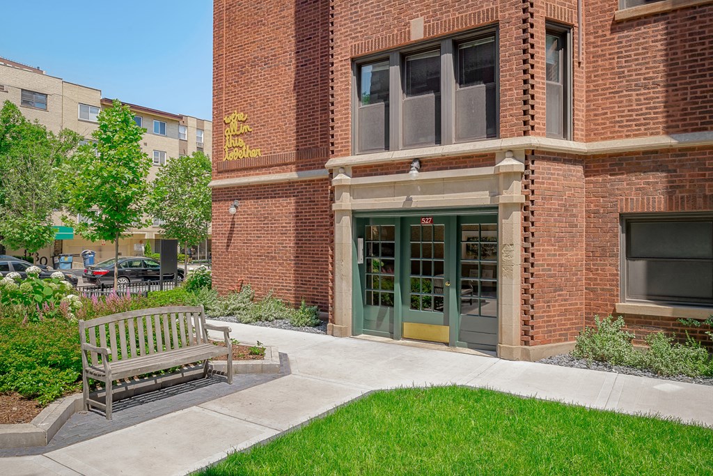 a bench in front of a brick building with a green door