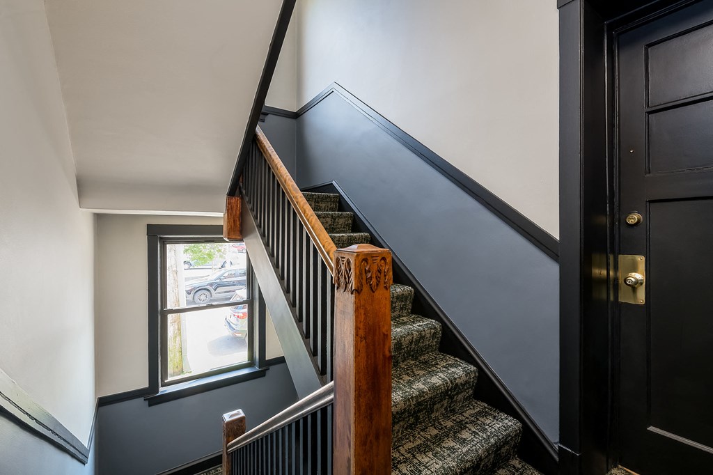 a stairway with carpeted stairs next to a window