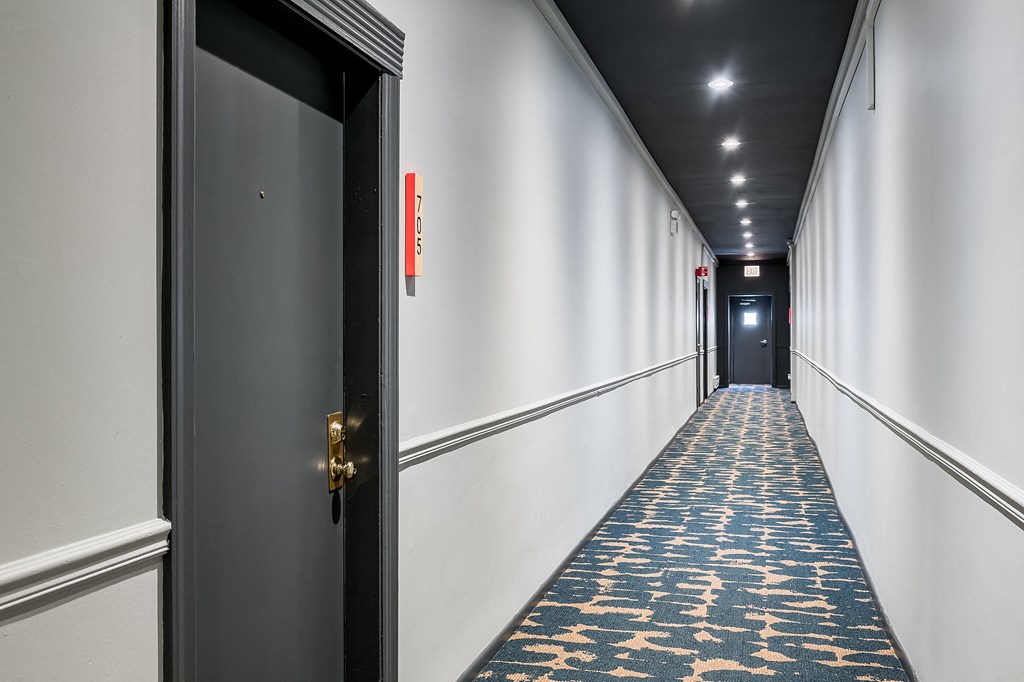 a hallway with a black door and a blue and yellow carpet