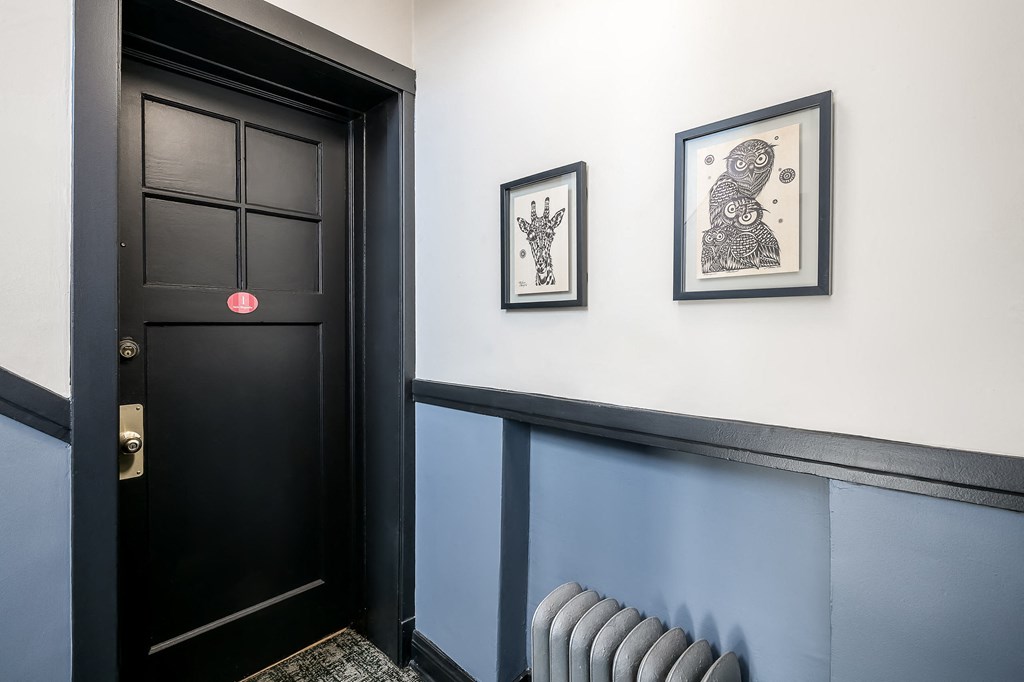 a hallway with a black door and pictures on the wall