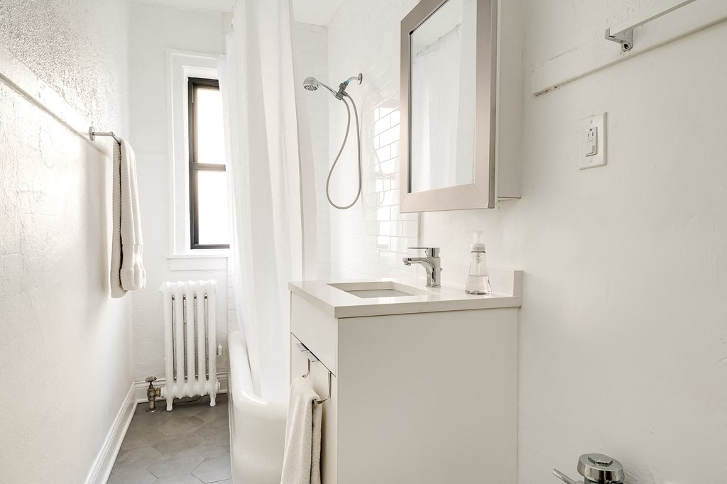 a small bathroom with a sink and shower and a window