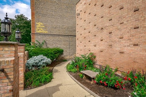 a garden with flowers and a bench in front of a brick building