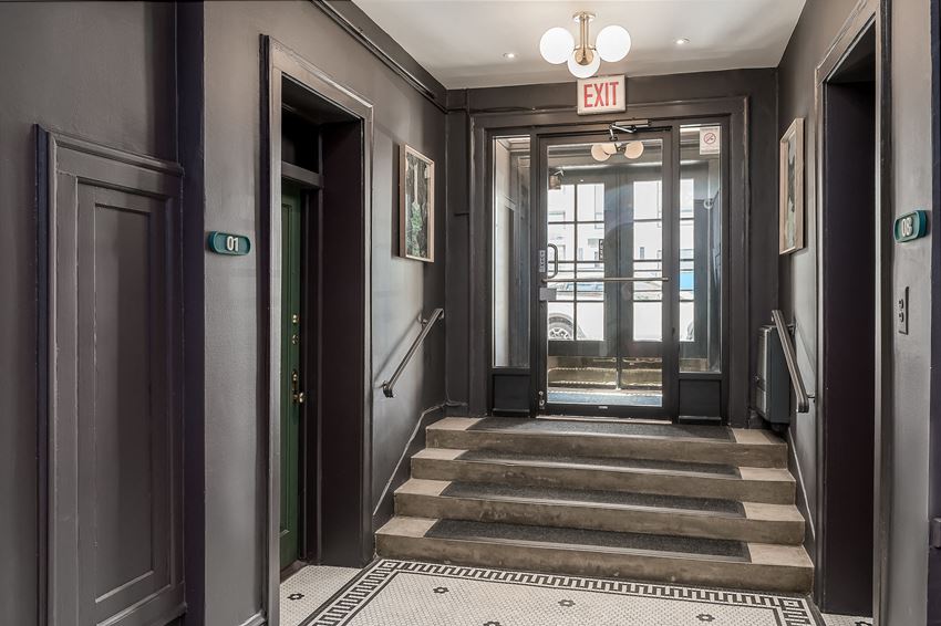 a hallway with stairs and doors and an exit sign
