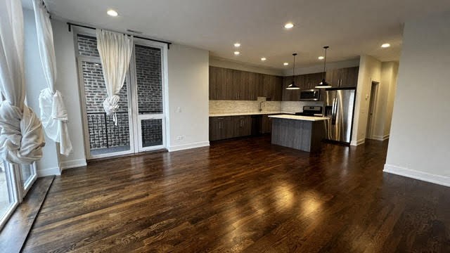 an empty living room and kitchen with wood floors