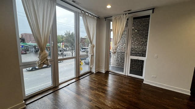 an empty living room with wood floors and large windows