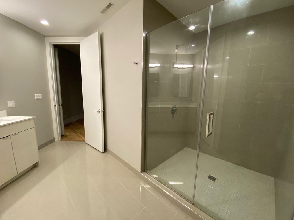 a bathroom with a shower and a sink and a door