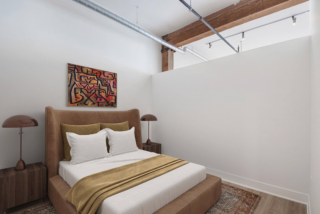 A bedroom with a bed, two lamps, and a painting on the wall.