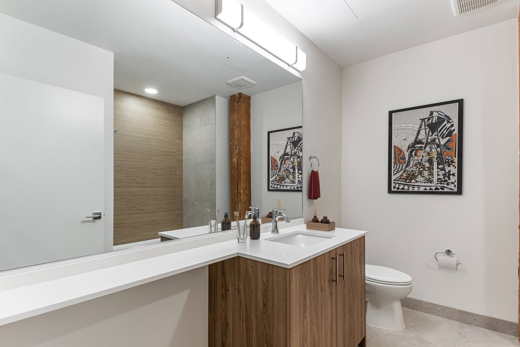A bathroom with a white counter top and a wooden cabinet.