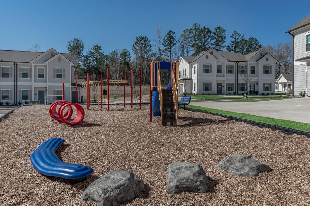 an empty playground with rocks and slides in front of apartment buildings