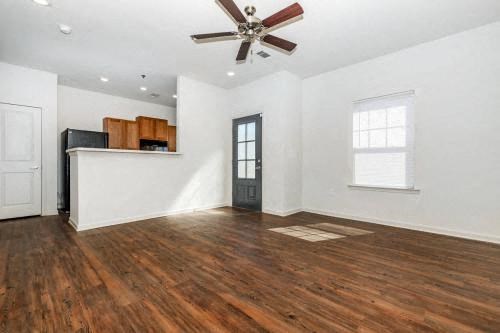 an empty living room with a ceiling fan and a kitchen