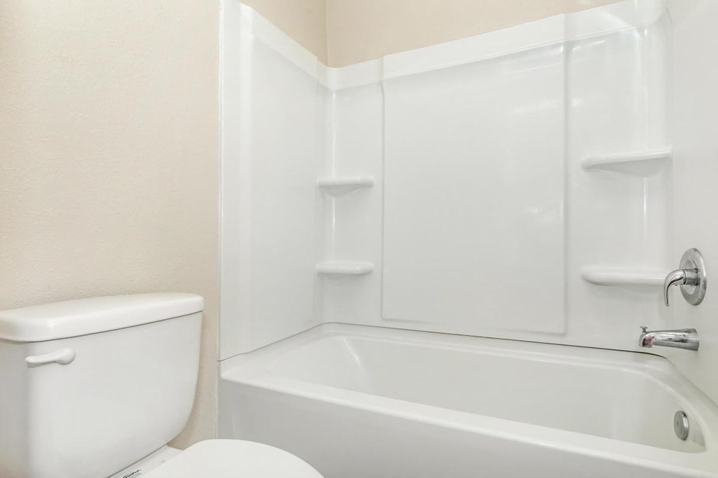 a white bathroom with a toilet and a tub