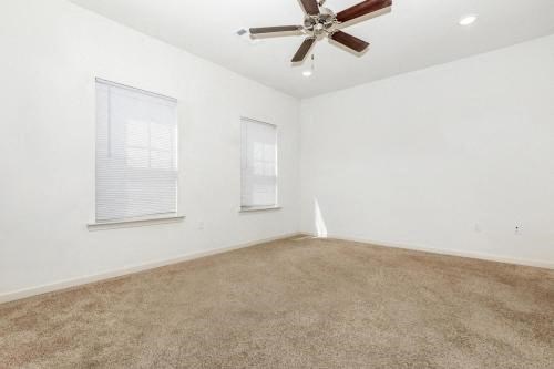 an empty room with a ceiling fan and two windows
