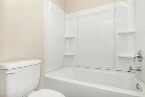 a white bathroom with a toilet and a bath tub