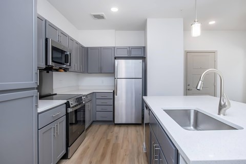 A modern kitchen with a stainless steel refrigerator and a white countertop.