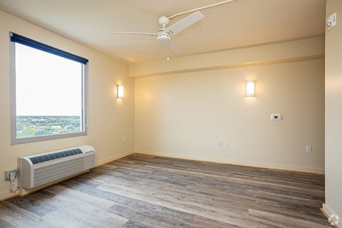 a living room with wood floors and a window and a ceiling fan