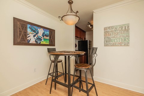 A dining room with a table and chairs and a painting on the wall. at The Cove at State Street Apartments, Baton Rouge