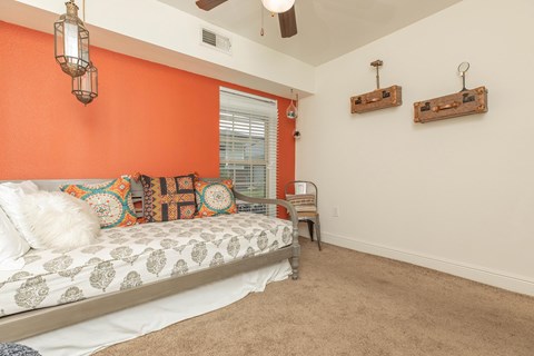 A bedroom with orange walls and a bed with a white comforter. at The Cove at State Street Apartments, Baton Rouge