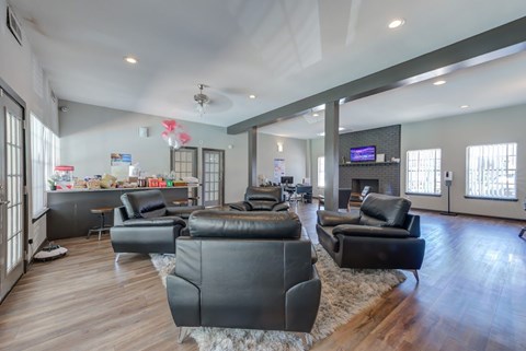 A living room with black leather furniture and a flat screen TV.