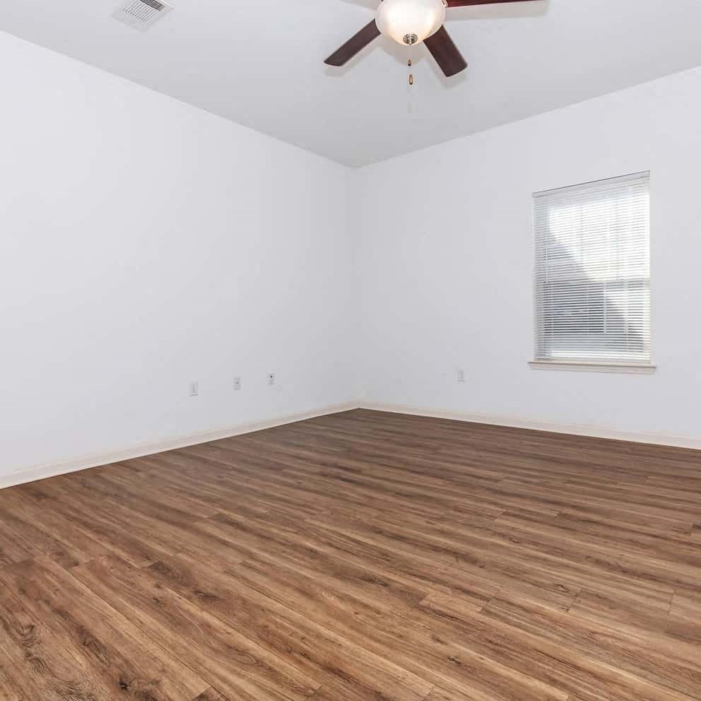 an empty room with wooden floors and a ceiling fan