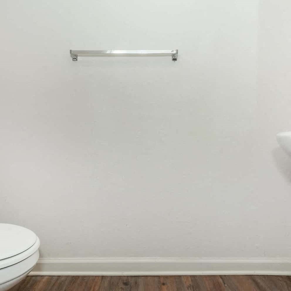 a white bathroom with a toilet and a towel rack