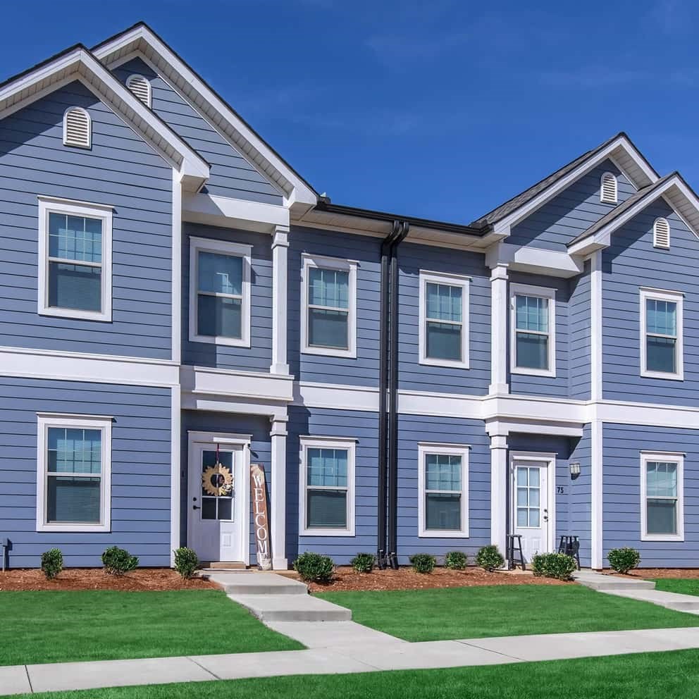 a blue and white house with green grass and a sidewalk
