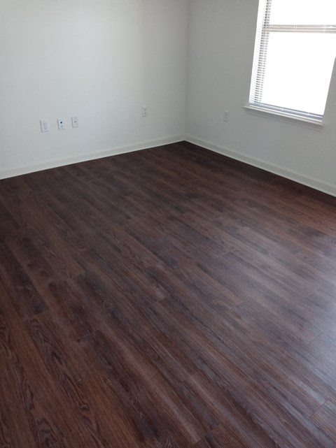an empty room with wooden floors and a window
