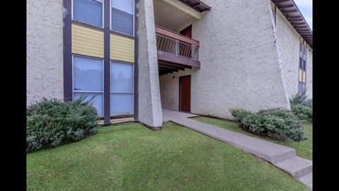 A building with a balcony and a small garden in front.